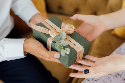 Two people exchange a candle and gift box, showing why candles are a good gift.