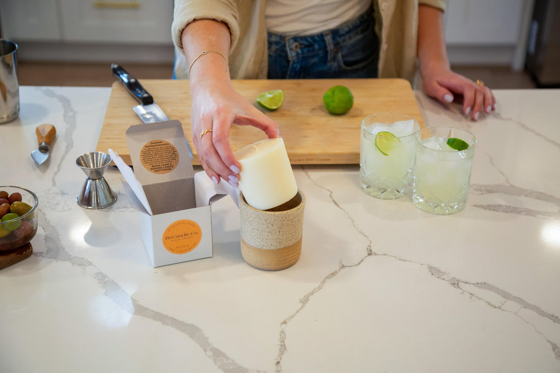 Woman placing a soy wax refill into a ReCandle Co. ceramic vessel on a kitchen counter, showcasing the refillable candle system