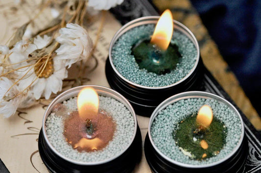 Three lit travel candles with cotton wicks and textured wax beads, in earthy green and copper tones.