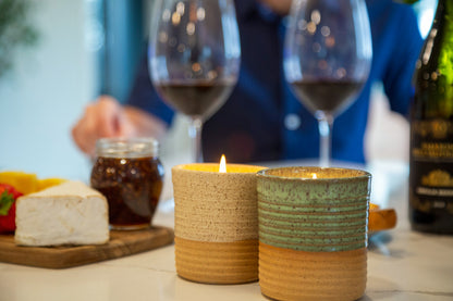 Two lit ReCandle Co., refillable candles sit on a counter next to a charcuterie board and two glasses of wine.