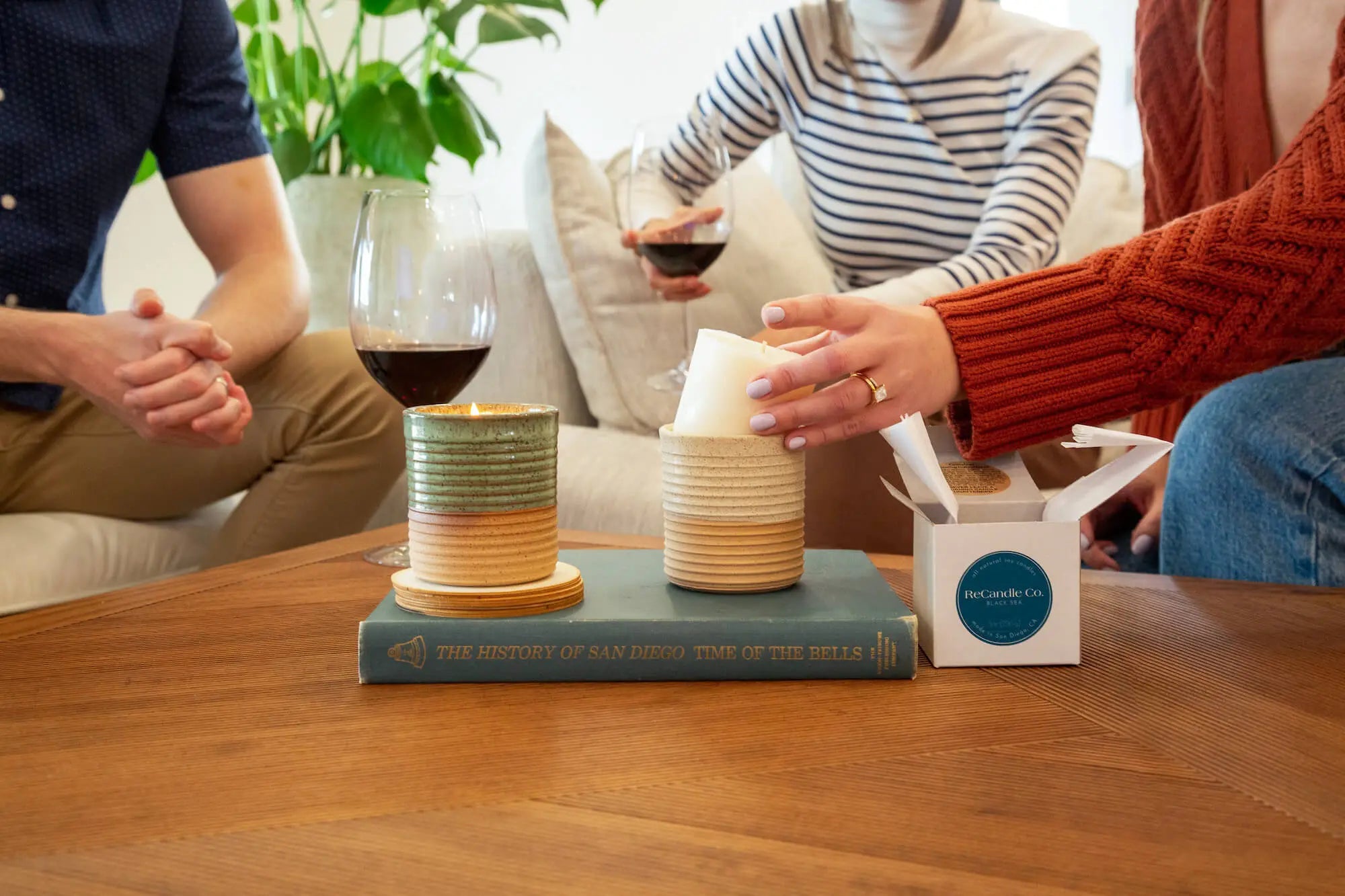 Two ReCandle Co. refillable candles on a table. One reusable candle is being refilled with a soy wax refill.