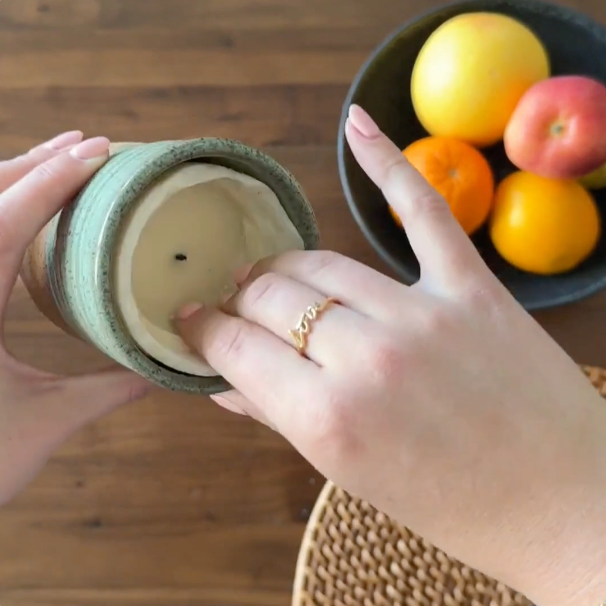 A product overview of a ReCandle Co. refillable candle. A person removes finished candle wax from the refillable candle, and replaces it with a new natural soy wax candle refill.