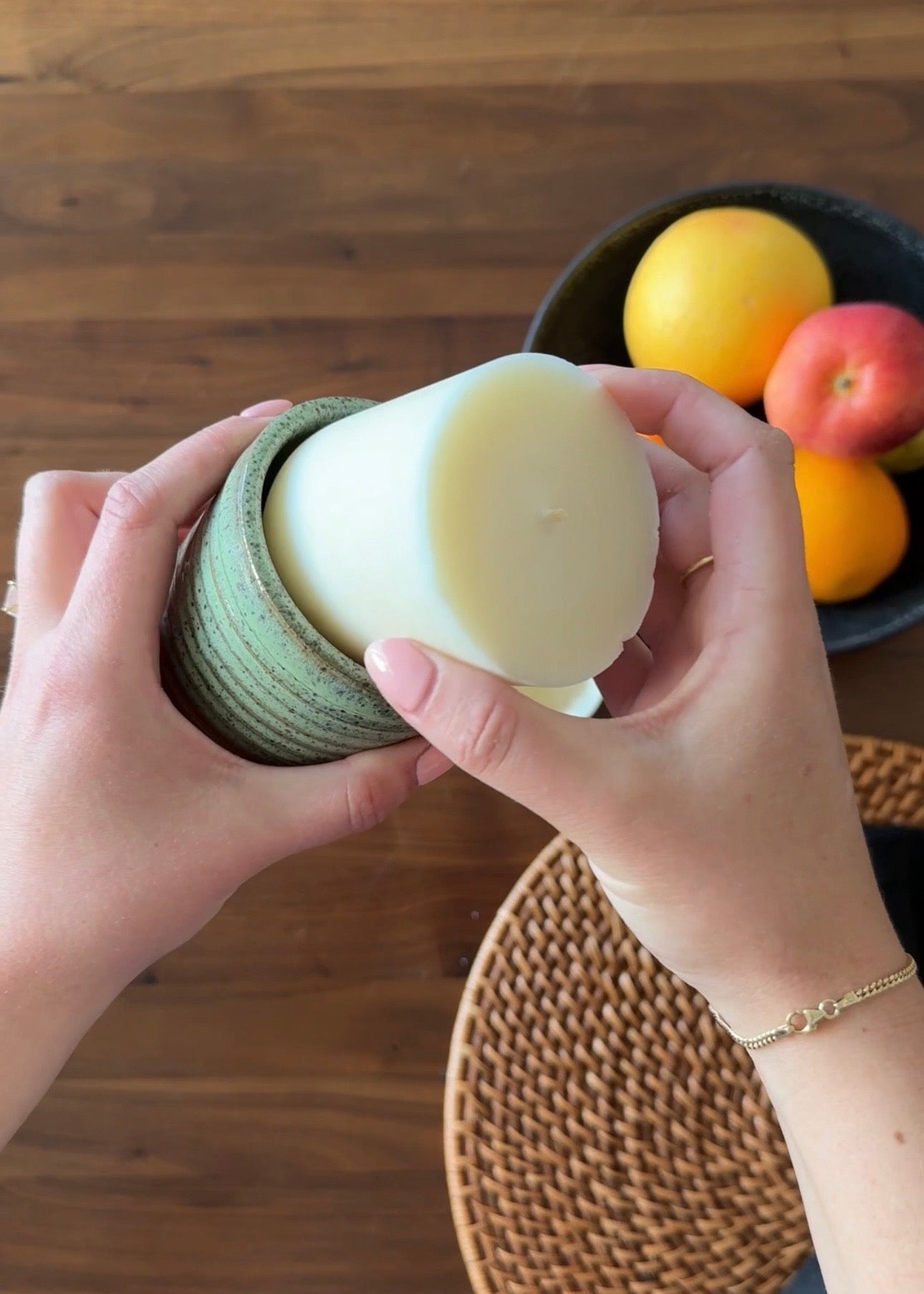 A hand placing a candle refill into a reusable candle jar