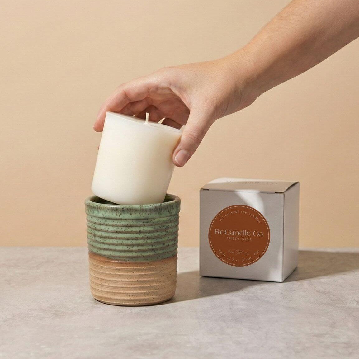 Inserting Amber Noir candle refill into sustainable teal ceramic refillable candle jar