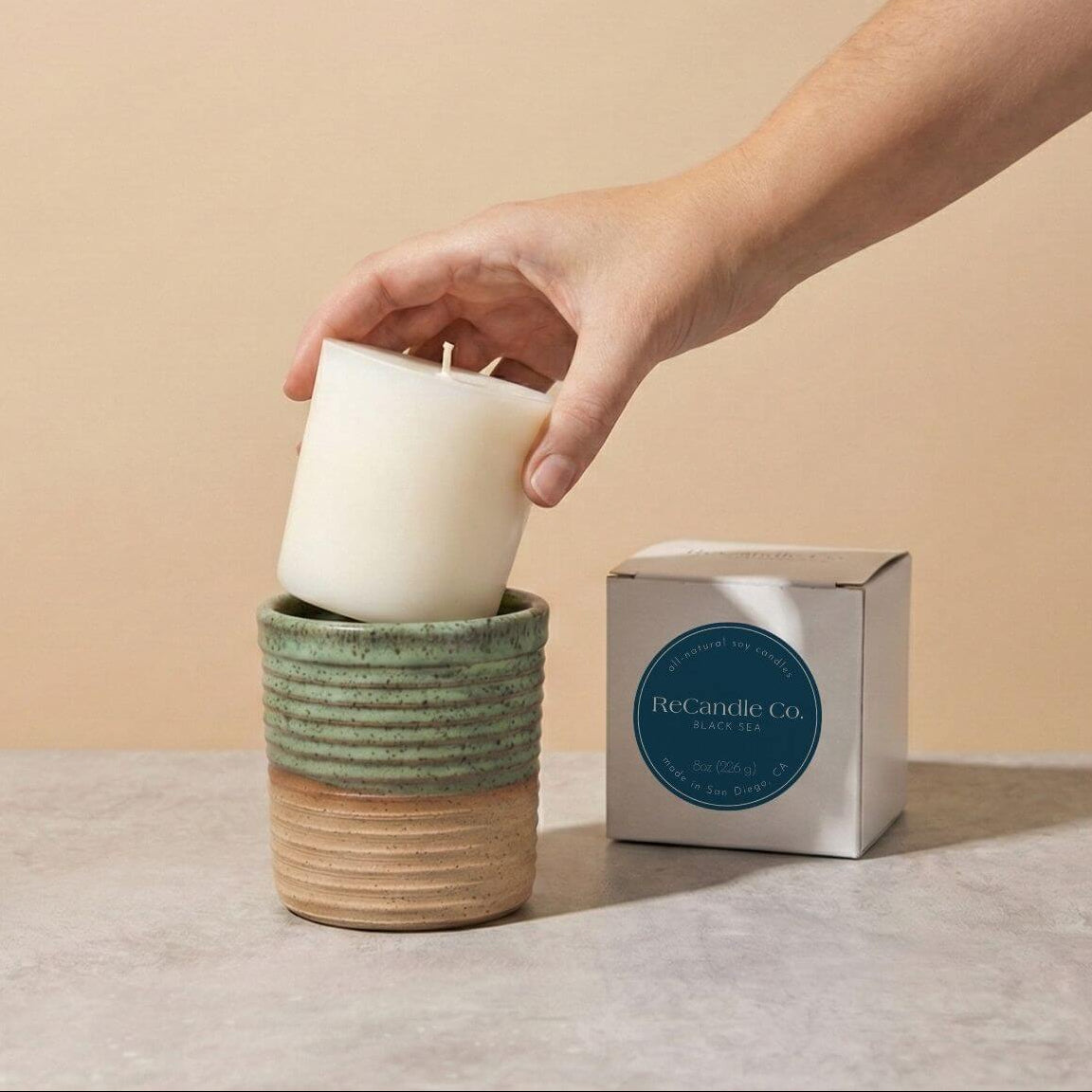 Inserting Black Sea candle refill into sustainable teal ceramic refillable candle jar