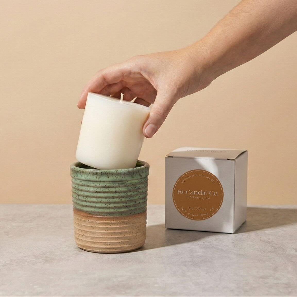 Inserting Pumpkin Chai candle refill into sustainable teal ceramic refillable candle jar