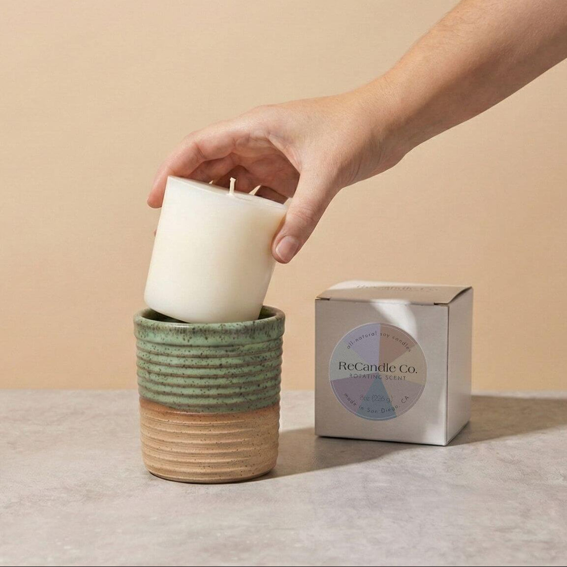 Inserting Rotating Scent candle refill into sustainable teal ceramic refillable candle jar