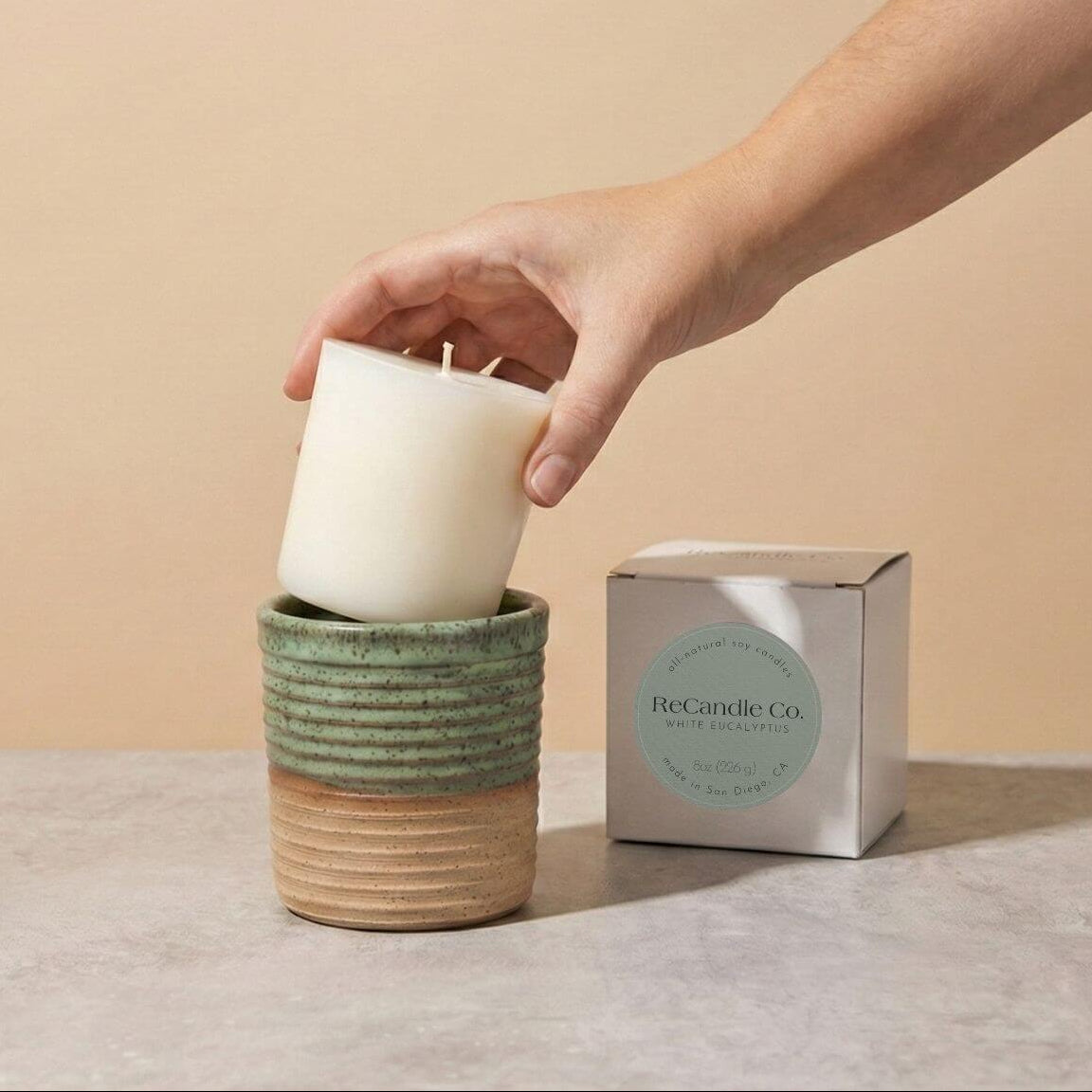 Inserting White Eucalyptus candle refill into sustainable teal ceramic refillable candle jar
