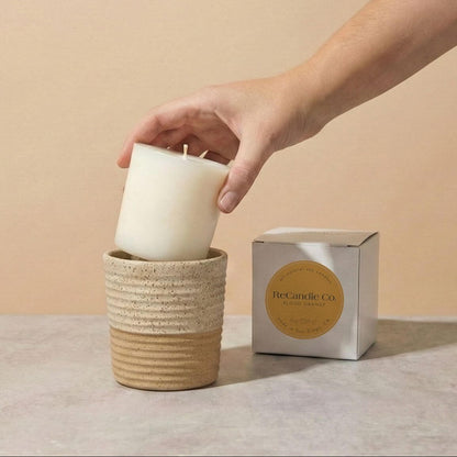 Person placing Blood Orange soy candle refill into walnut ceramic refillable candle holder