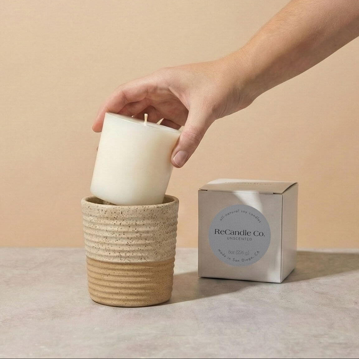 Person placing Unscented soy candle refill into walnut ceramic refillable candle holder