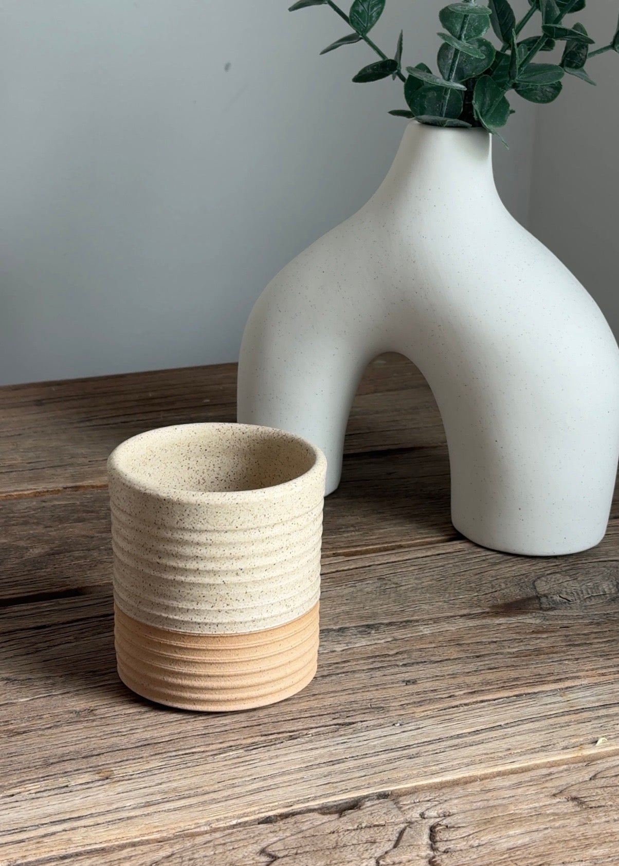 A walnut refillable candle jar on a side table